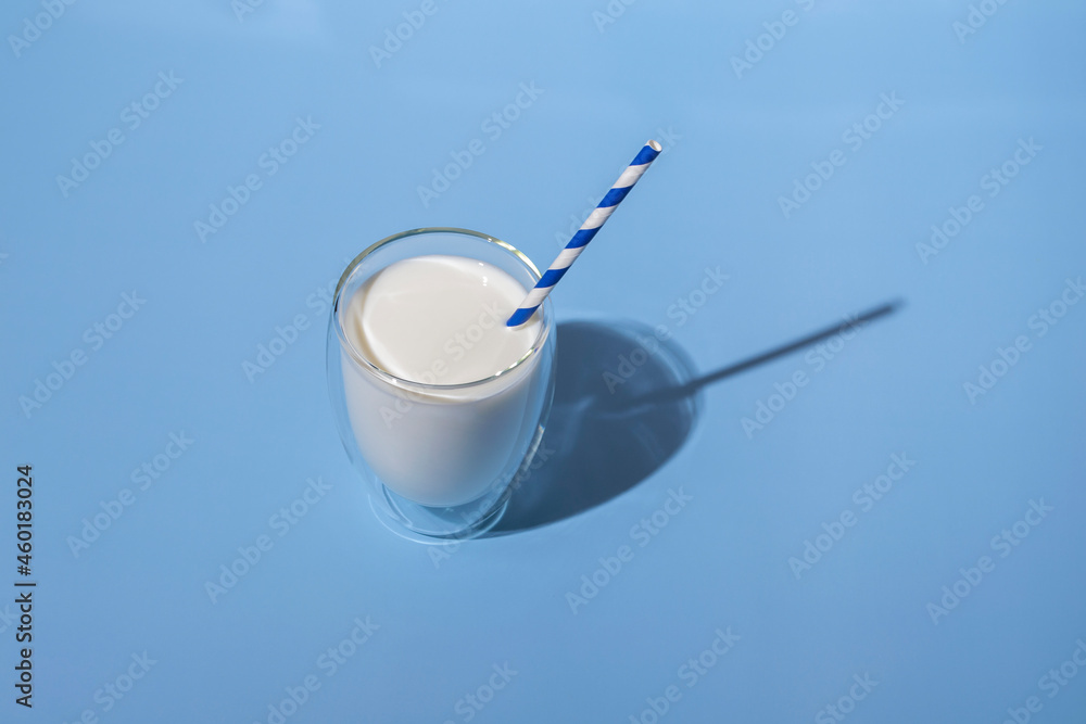 World Milk Day. Glass of milk with a straw against blue background. Sample. Package. World Milk Day. Glass of milk with a straw against blue background. Sample. Package.