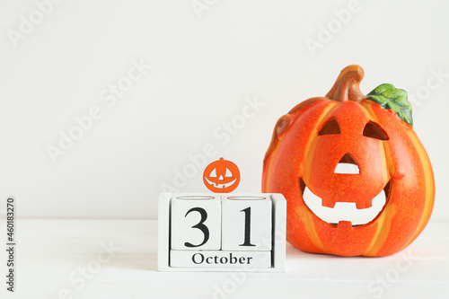 Halloween card with copy space for congratulation. Calendar dated October 31 and Jack-o-latern on white table. Selective focus