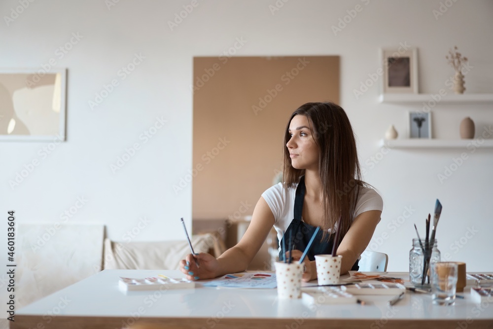Beautiful Female Artist In Her Studio. Female drawing in album with watercolor paints and paintbrush Beautiful Female Artist In Her Studio. Female drawing in album with watercolor paints and paintbrush