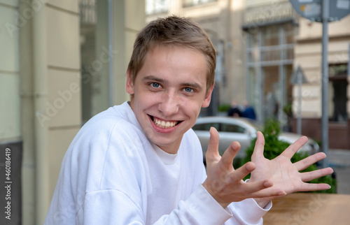 Fotografía An emotional portrait of a young guy in the summer on the street with his arms outstretched