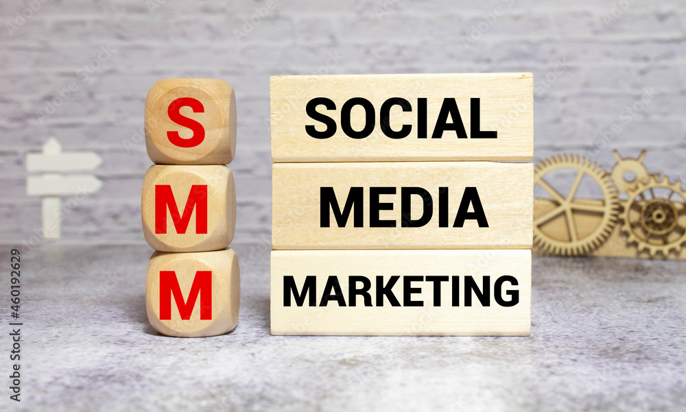 SMM - social media marketing - letters on wooden cubes on grey blue background SMM - social media marketing - letters on wooden cubes on grey blue background