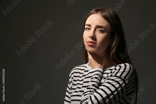 Sad young woman on dark bac...