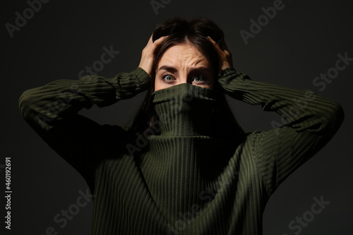 Scared young woman on dark ...