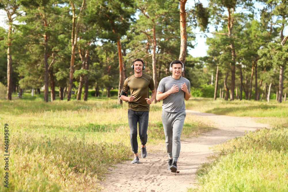 Sporty young men with headphones running in park Sporty young men with headphones running in park