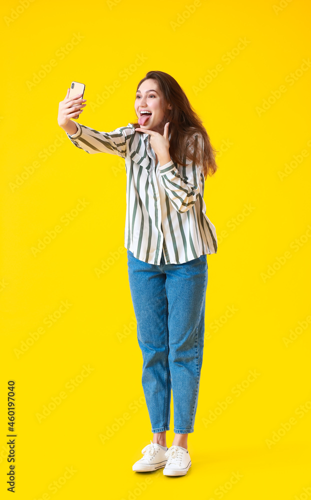 Beautiful young woman taking selfie on yellow background Beautiful young woman taking selfie on yellow background