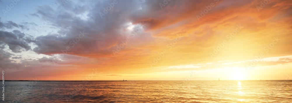 Baltic sea at sunset. Dramatic sky with glowing golden pink clouds, reflections in the water. Lighthouse. Setting sun. Epic seascape. Abstract natural pattern, texture, background, concept image - obrazy, fototapety, plakaty 