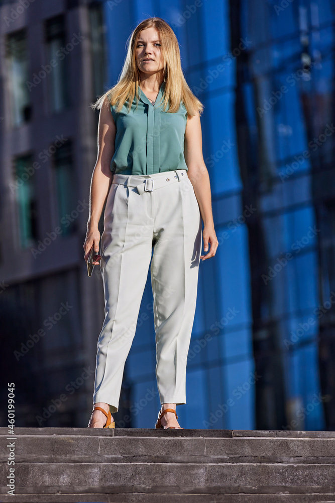 White woman with blond hair stands near business center.