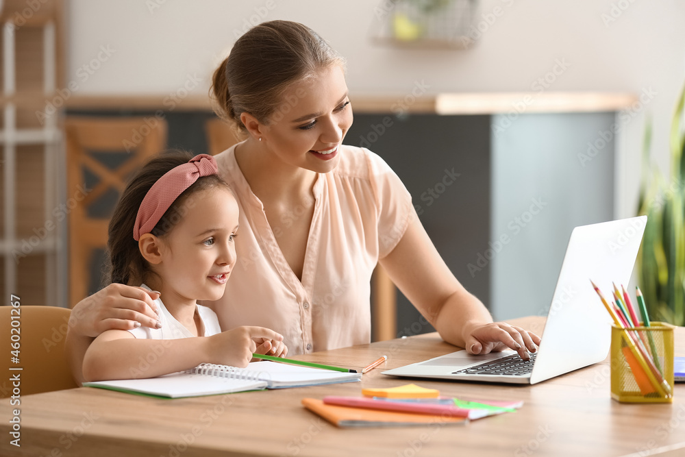 Little girl with her mother doing lessons online at home Little girl with her mother doing lessons online at home
