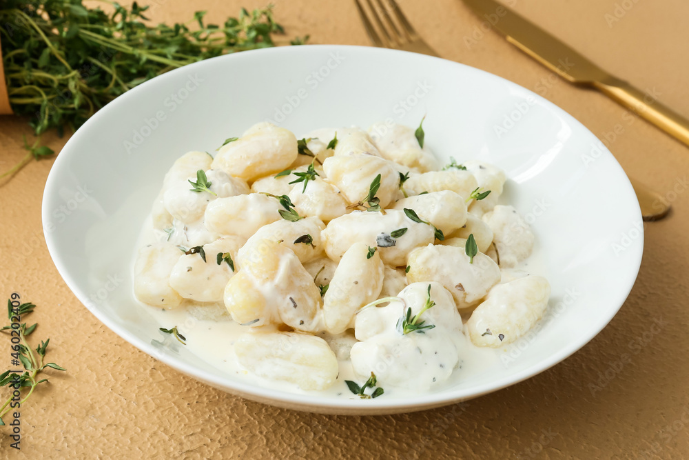 Plate of delicious gnocchi with creamy sauce on beige background Plate of delicious gnocchi with creamy sauce on beige background