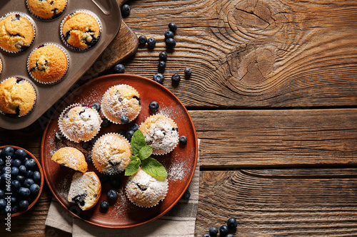Composition with tasty blueberry muffins and berries on wooden background, closeup