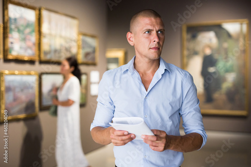Portrait of European adult man standing in gallery and watching exposition