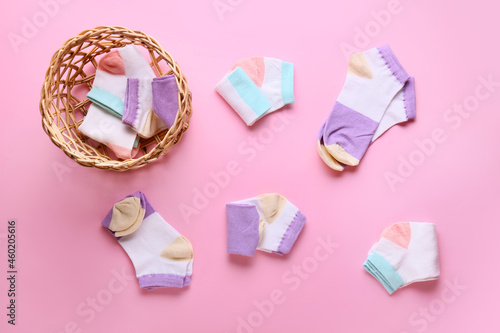 Wicker basket and different socks on color background