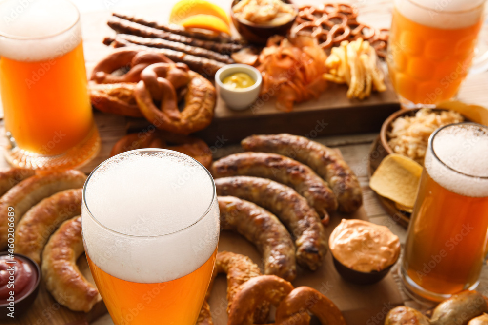 Glasses of cold beer, board with Bavarian sausages and snacks on table, closeup. Oktoberfest celebration Glasses of cold beer, board with Bavarian sausages and snacks on table, closeup. Oktoberfest celebration