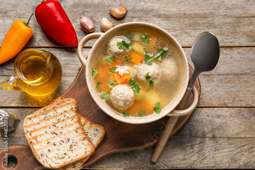 Bowl with tasty meatball soup, bread and spices on wooden background
