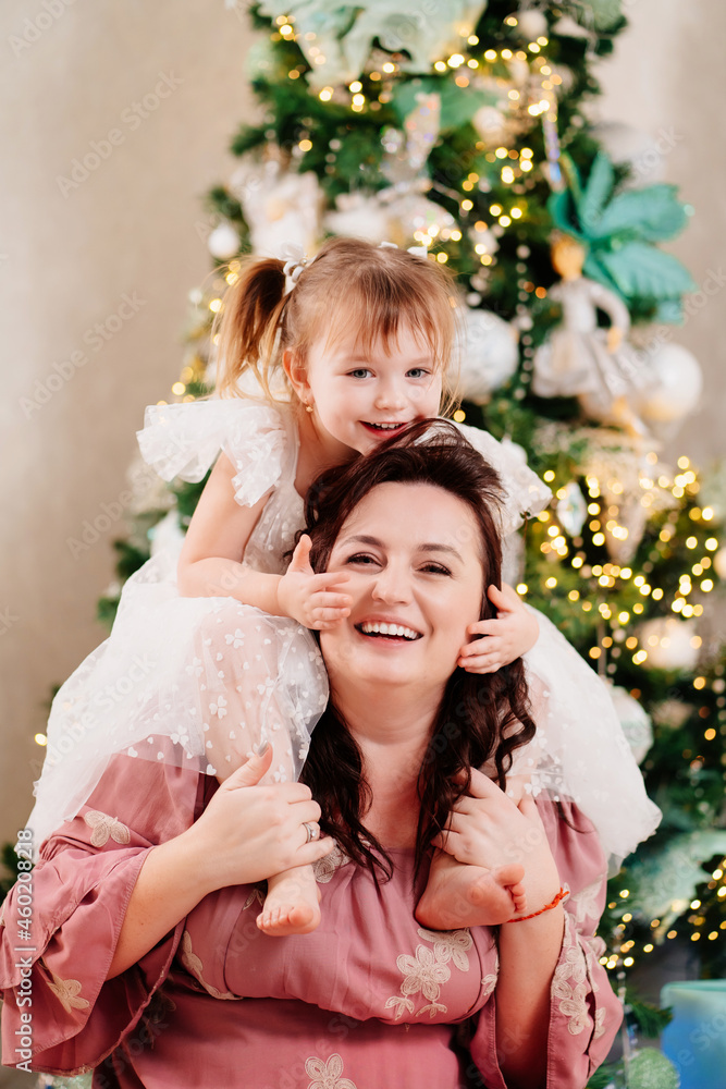 mom and daughter play at the Christmas tree. mom and daughter play at the Christmas tree.