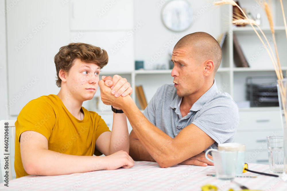 Obraz premium Happy father and son competing in arm wrestling