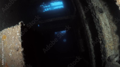 Unique underwater scuba divers view penetrating through a hatch of a sunken shipwreck to reveal a dark chamber of the recently scuttled Navy ship the Ex-HMAS Tobruk photo