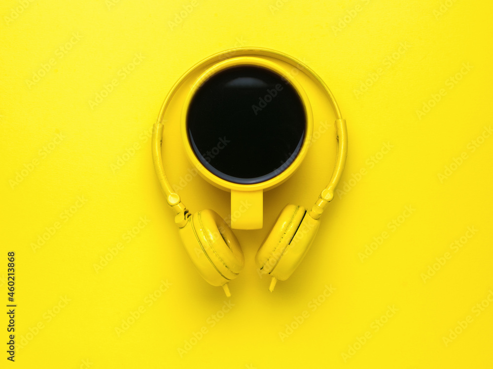 Yellow coffee cup and yellow headphones on a bright yellow background. Yellow coffee cup and yellow headphones on a bright yellow background.