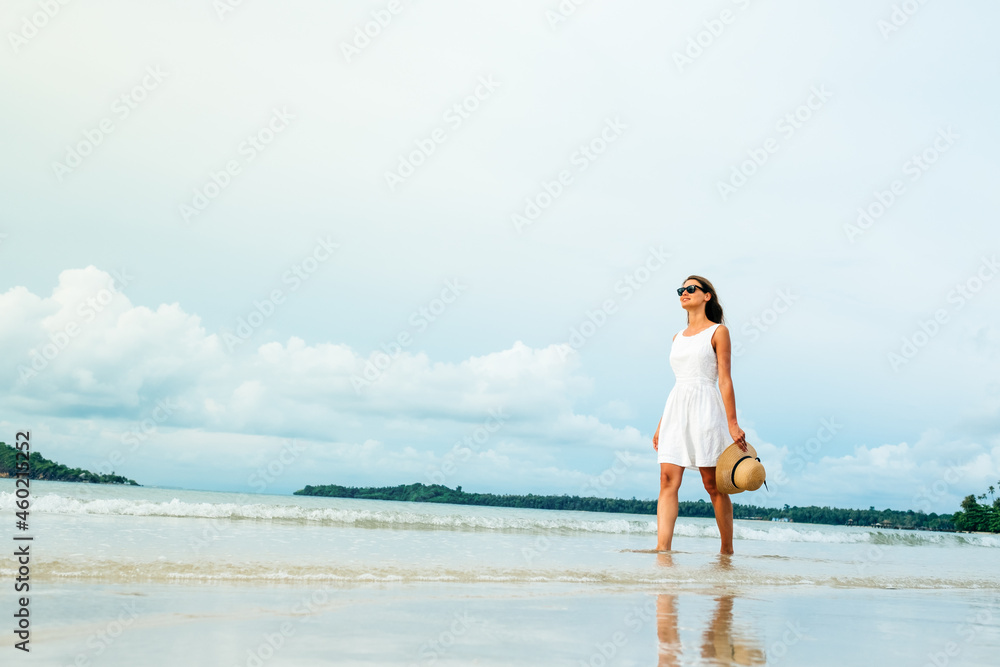 Happy young woman wearing beautiful white dress walking on the beach Happy young woman wearing beautiful white dress walking on the beach