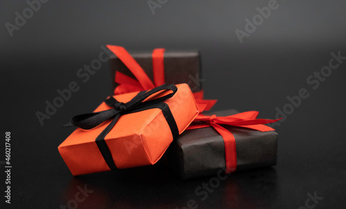 three gifts on a black background, red and black ribbons, black Friday concept