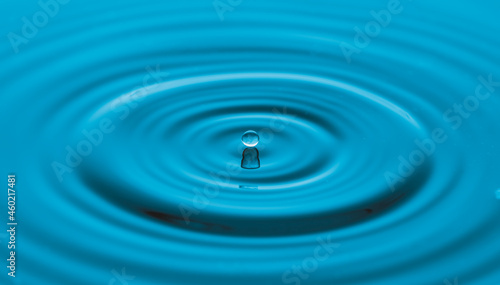 Water drop on water surface with blue light effects background.