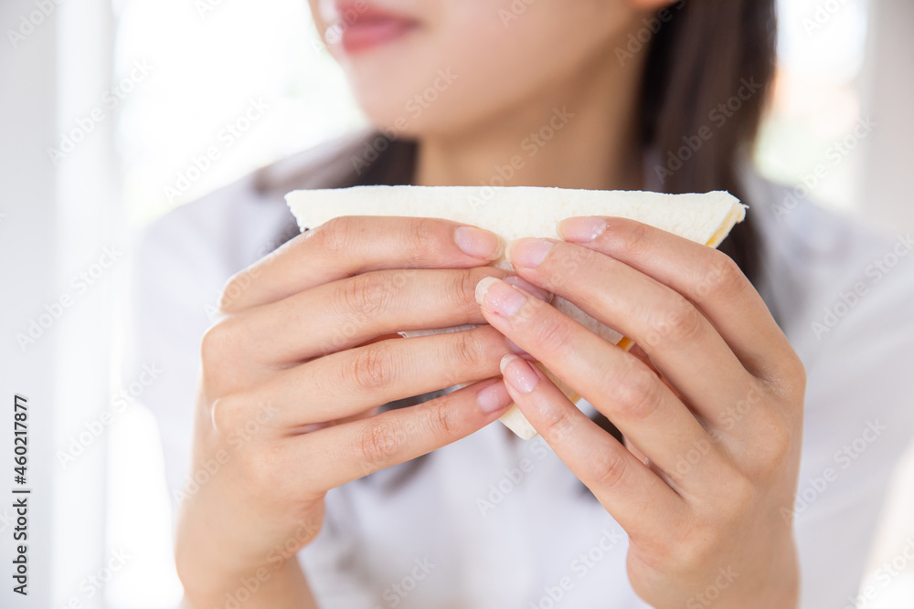 朝食をとる女性　サンドウィッチをもつ女性