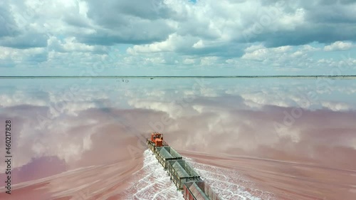 An old train travels on a railway laid in the water across a salt lake. Aerial view. Extraction of salt in Lake Bursol. Russia.  photo