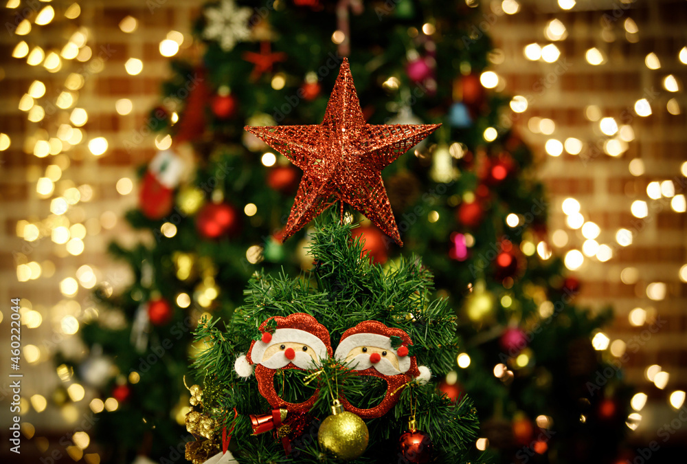 Close up shot of sparkling glossy glitter red star with cute Santa Claus decorating hanging dolls on top of green Christmas pine tree celebrating traditional festive night event on blurred background Close up shot of sparkling glossy glitter red star with cute Santa Claus decorating hanging dolls on top of green Christmas pine tree celebrating traditional festive night event on blurred background