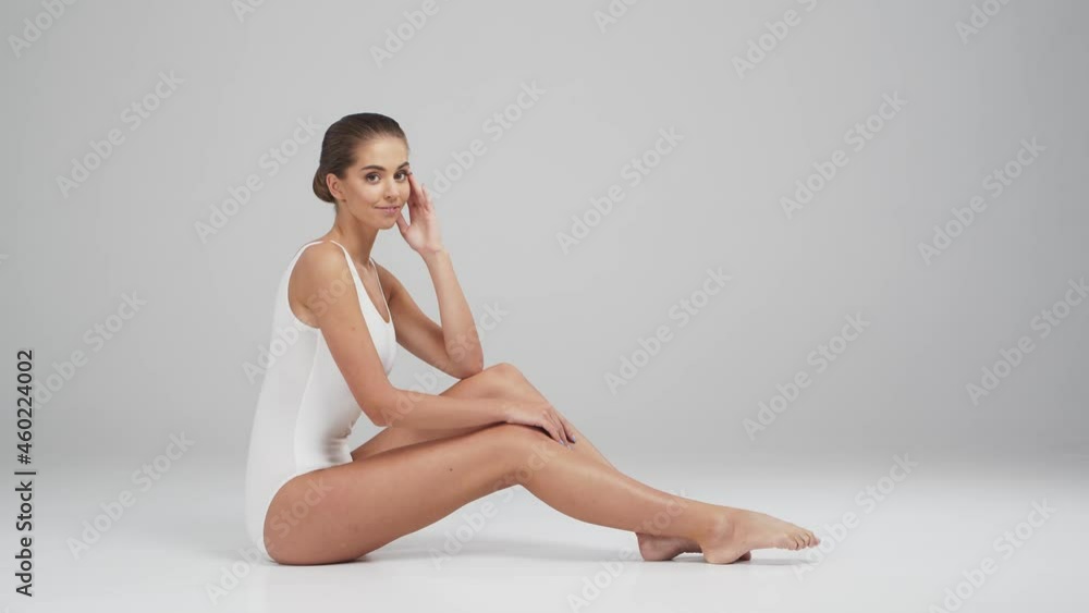 Young, beautiful, fit and natural blond woman in white swimsuit applying moisturizing cream. Massage, skin care, cellulite removal, sport and weight loss. Young, beautiful, fit and natural blond woman in white swimsuit applying moisturizing cream. Massage, skin care, cellulite removal, sport and weight loss.