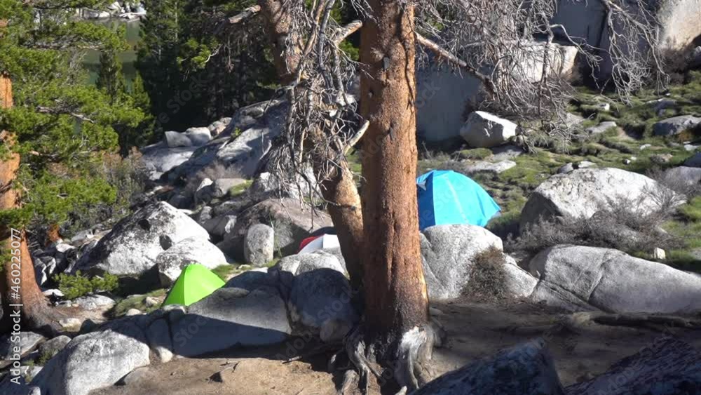 Hiking and Camping in Wilderness, Tents Between Rocks in Landscape of Mountain on Sunny Day Hiking and Camping in Wilderness, Tents Between Rocks in Landscape of Mountain on Sunny Day