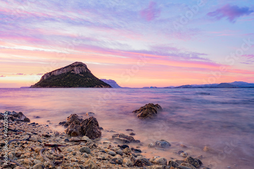 Stunning view of Figarolo island during a romantic and relaxing sunrise with a calm water and some rocks in the foreground. Golfo Aranci, Sardinia, Italy.