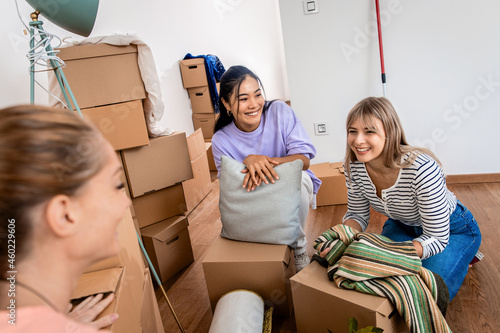 Canvas Print Three female friends carrying boxes into new home.