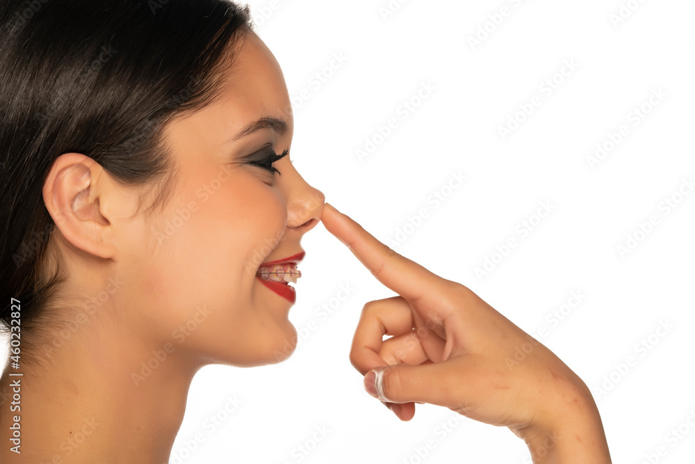 a young smiling beautiful woman touches her nose a young smiling beautiful woman touches her nose
