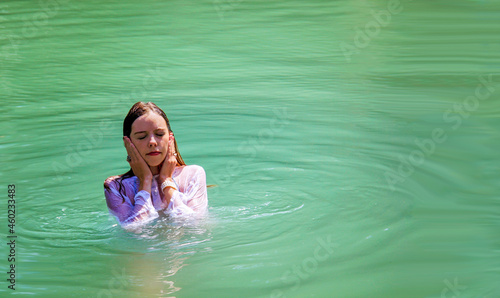 Fotografie, Tablou Christian Pilgrim girl take a symbolic baptism in the Jordan River in North Isra