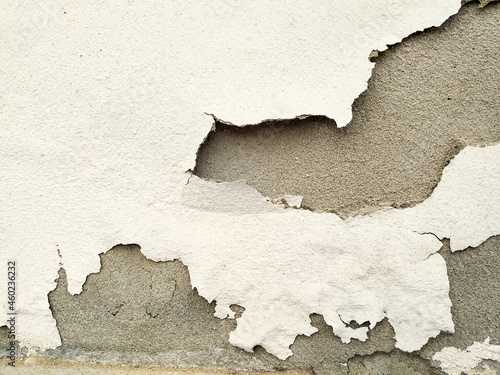 The wall of theold concrete house, painted in white. Peeling, falling paint on an old surface. photo