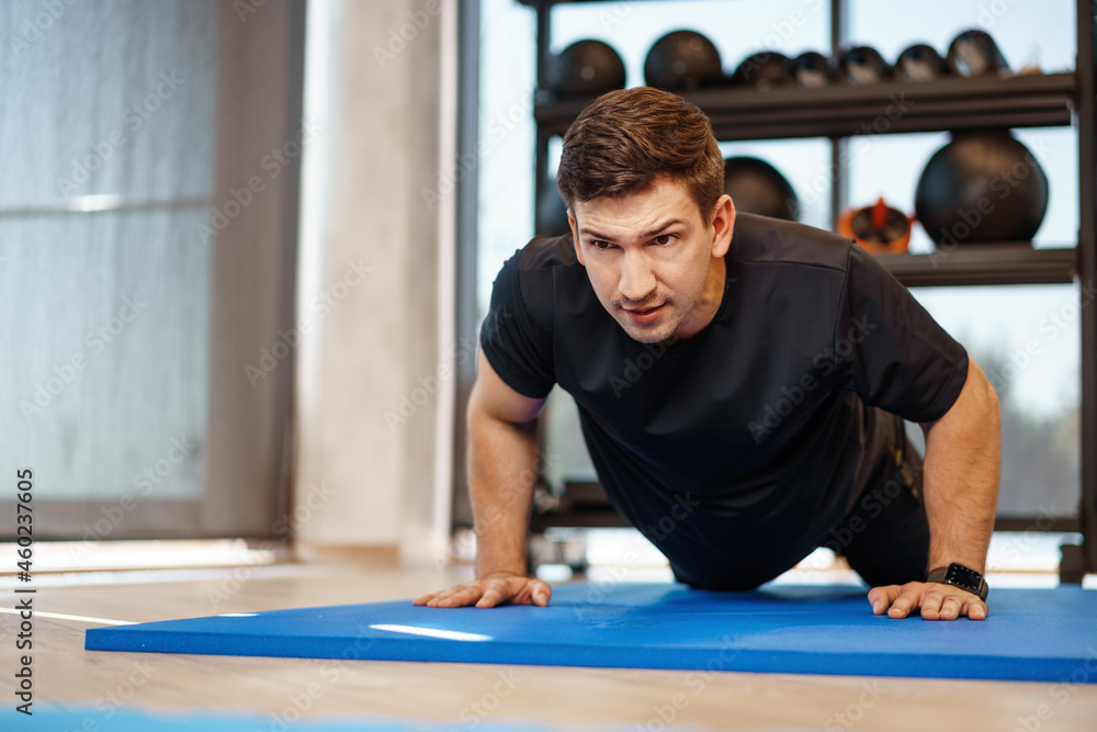 Fototapeta premium Young athletic man doing push-ups in a gym, close up