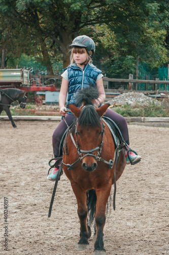 Little girl goes in for equestrian sports. The child is riding a horse.