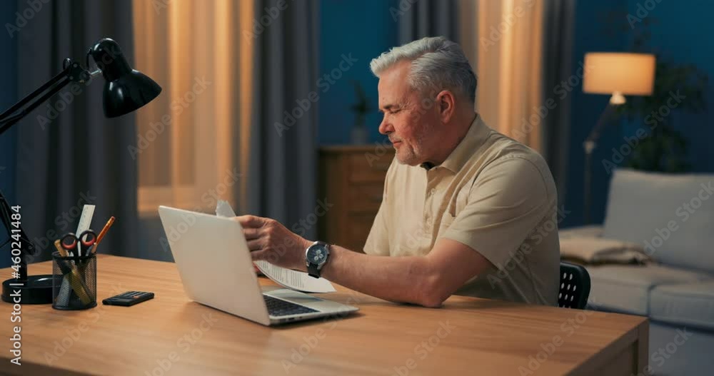 Senior citizen talks online, laptop with daughter, asks for help filing documents, social networking conversation, remote connection, webcam, late evening in home office Senior citizen talks online, laptop with daughter, asks for help filing documents, social networking conversation, remote connection, webcam, late evening in home office