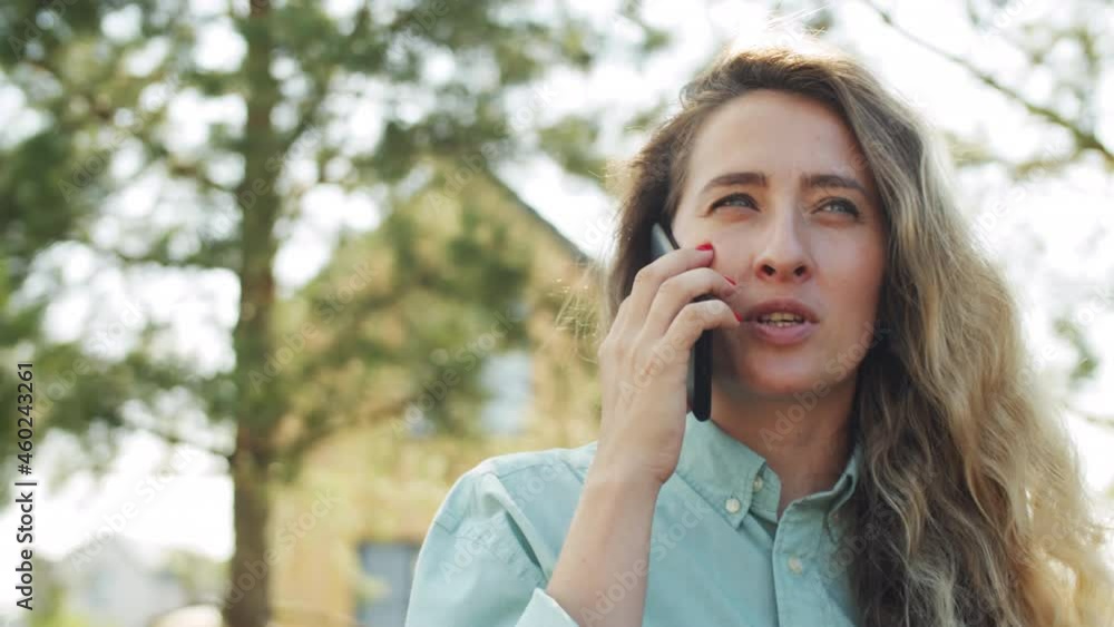 Chest up shot of young Caucasian woman holding to go coffee and chatting on mobile phone while standing outdoors in park on summer day Chest up shot of young Caucasian woman holding to go coffee and chatting on mobile phone while standing outdoors in park on summer day