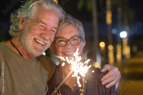 Fotografie Close-up on beautiful senior couple in outdoor at night having fun with sparkles lights