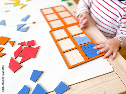 The child collects puzzles. Educational wooden toy for learning. Montessori materials. Fine motor skills, hand-eye coordination. Children's leisure, nursery.The concept of early development. squares. 