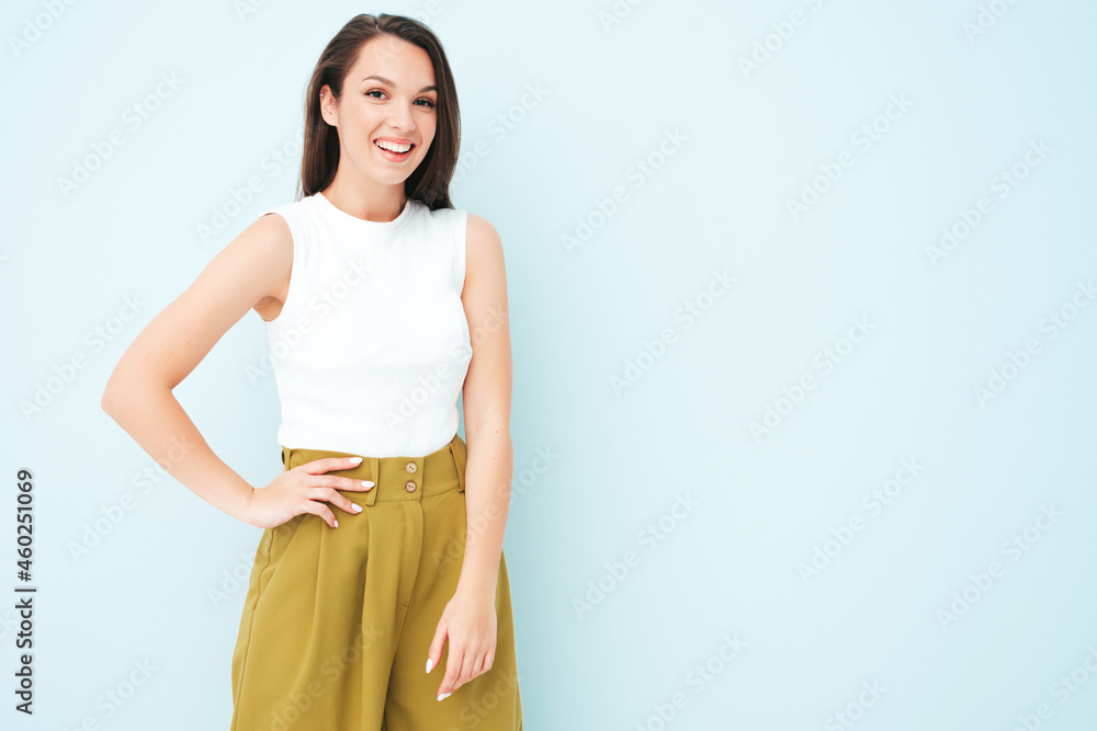 Young beautiful smiling female in trendy summer suit clothes. Sexy carefree woman posing near light blue wall in studio. Positive model having fun indoors. Cheerful and happy Young beautiful smiling female in trendy summer suit clothes. Sexy carefree woman posing near light blue wall in studio. Positive model having fun indoors. Cheerful and happy
