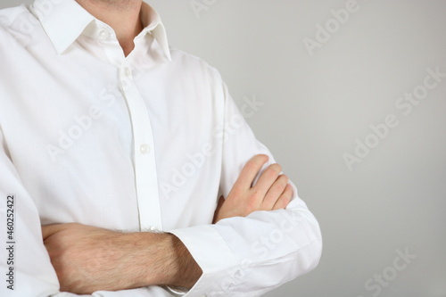 Elegant man wearing white shirt holds arms folded