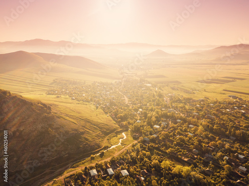 Panoramic aerial view of the sunrise over a picturesque village among the hills and a small river