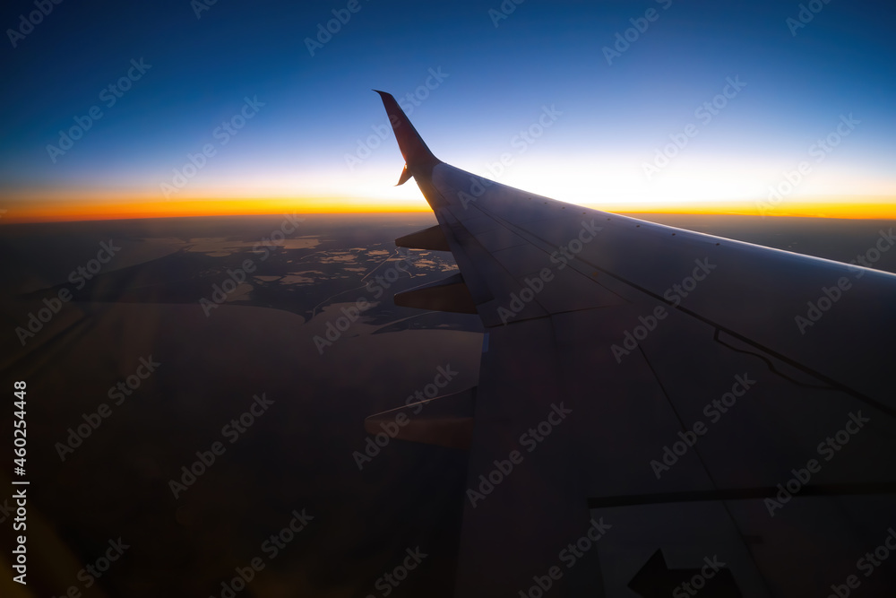 View of the wing of the plane through the window, sunset, clouds. Flight and tourism concept. Turkey