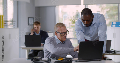 Billede på lærred Mixed-race it-technician fix laptop for mature businessman in office