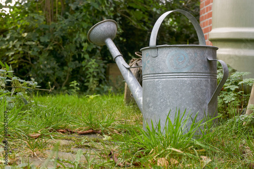 Zinc watering can in a garden. Low perspective image with copy space.