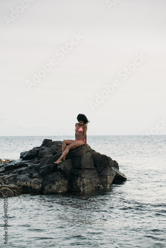 Woman sitting in rocks by the seashore
