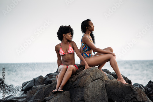 Two sisters sitting in rocks by the seashore