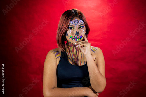 Young woman with makeup for halloween party, costume party, red background.